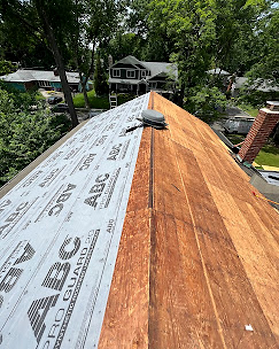 New synthetic underlayment installation across roof deck